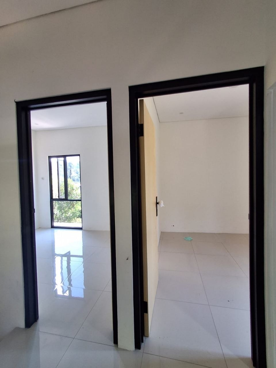 Kamar tidur utama rumah baru Megah Residence 2 Gunungpati Semarang, pintu kayu finishing gelap, jendela besar pencahayaan alami