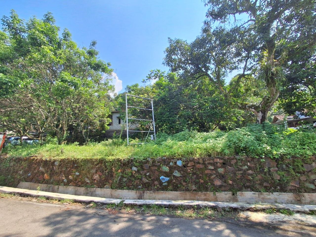 Tembok pagar batu warna-warni sisi kavling Sabrangan Village, tiang listrik di tengah.
