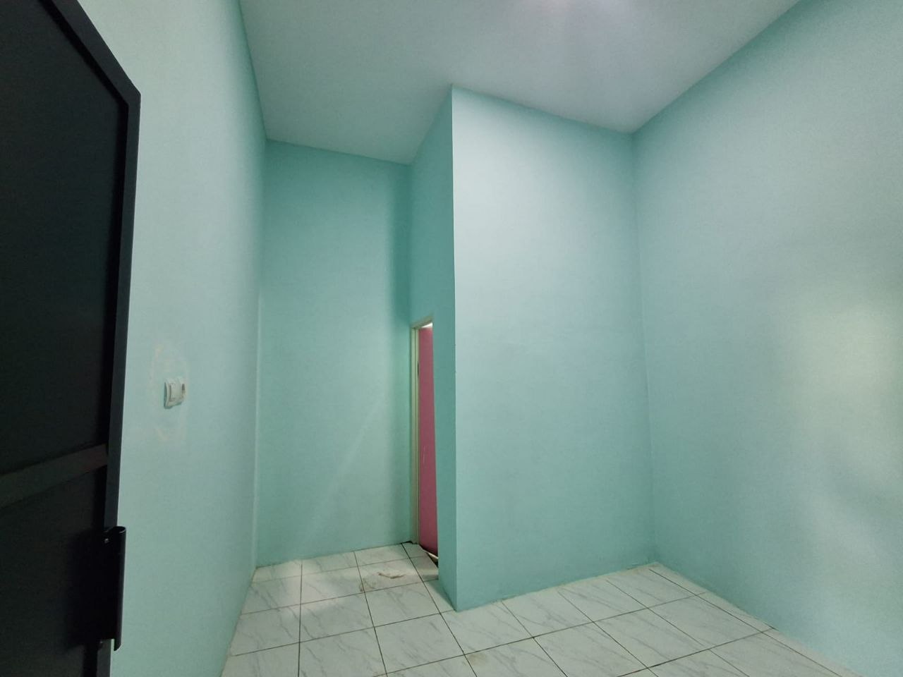 Interior kamar tidur kos Patemon Gunungpati dengan dinding biru muda, pintu ke kamar mandi dalam, lantai keramik putih