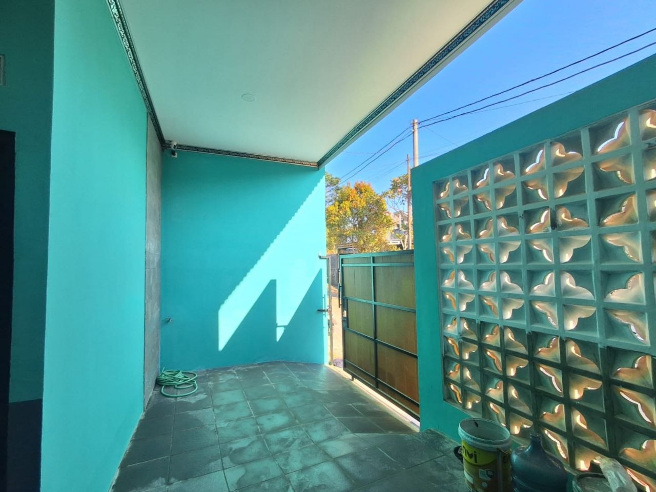 Area teras depan kos Patemon Gunungpati dengan roster glass block, pintu gerbang metal, dan lantai keramik